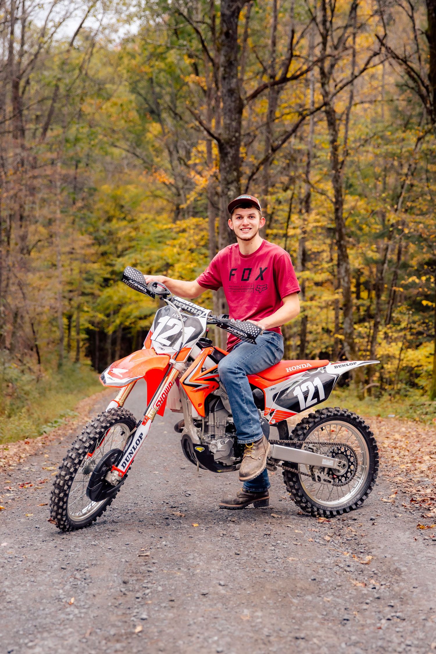 Boy posing with dirt bike on gravel road