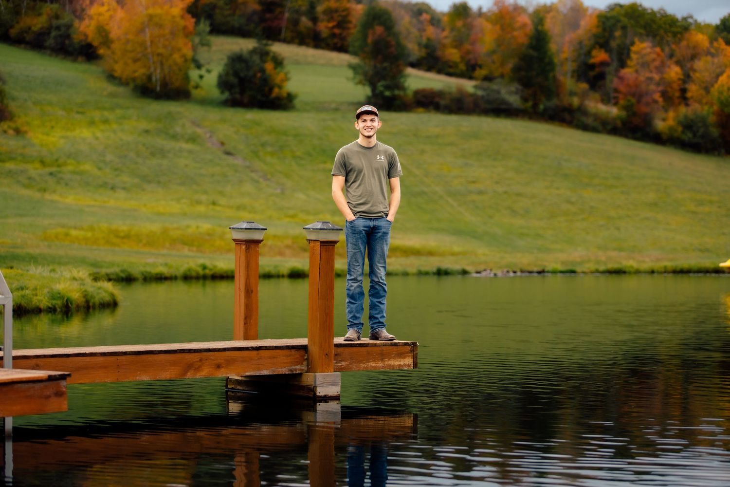 Boy standing on dock over pond with hands in pockets