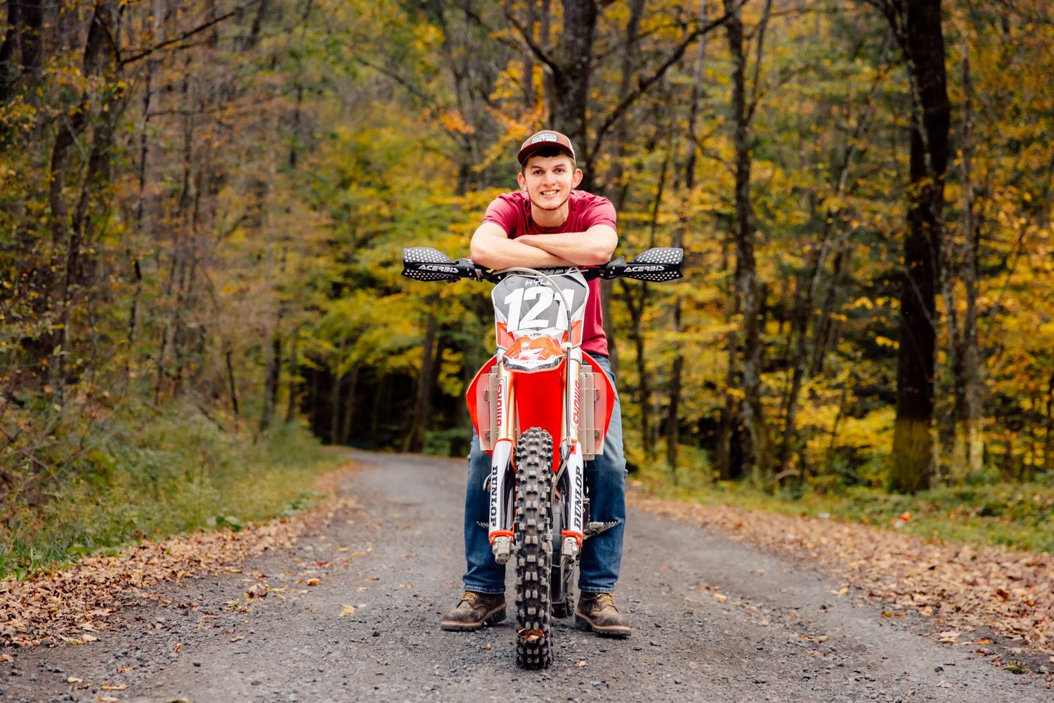 Boy posing with dirt bike on gravel road
