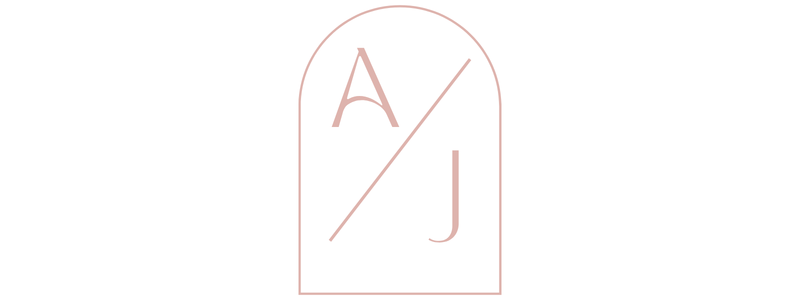 Elegant minimalist monogram logo featuring letters A and J with a diagonal slash inside an arch frame in soft rose pink.