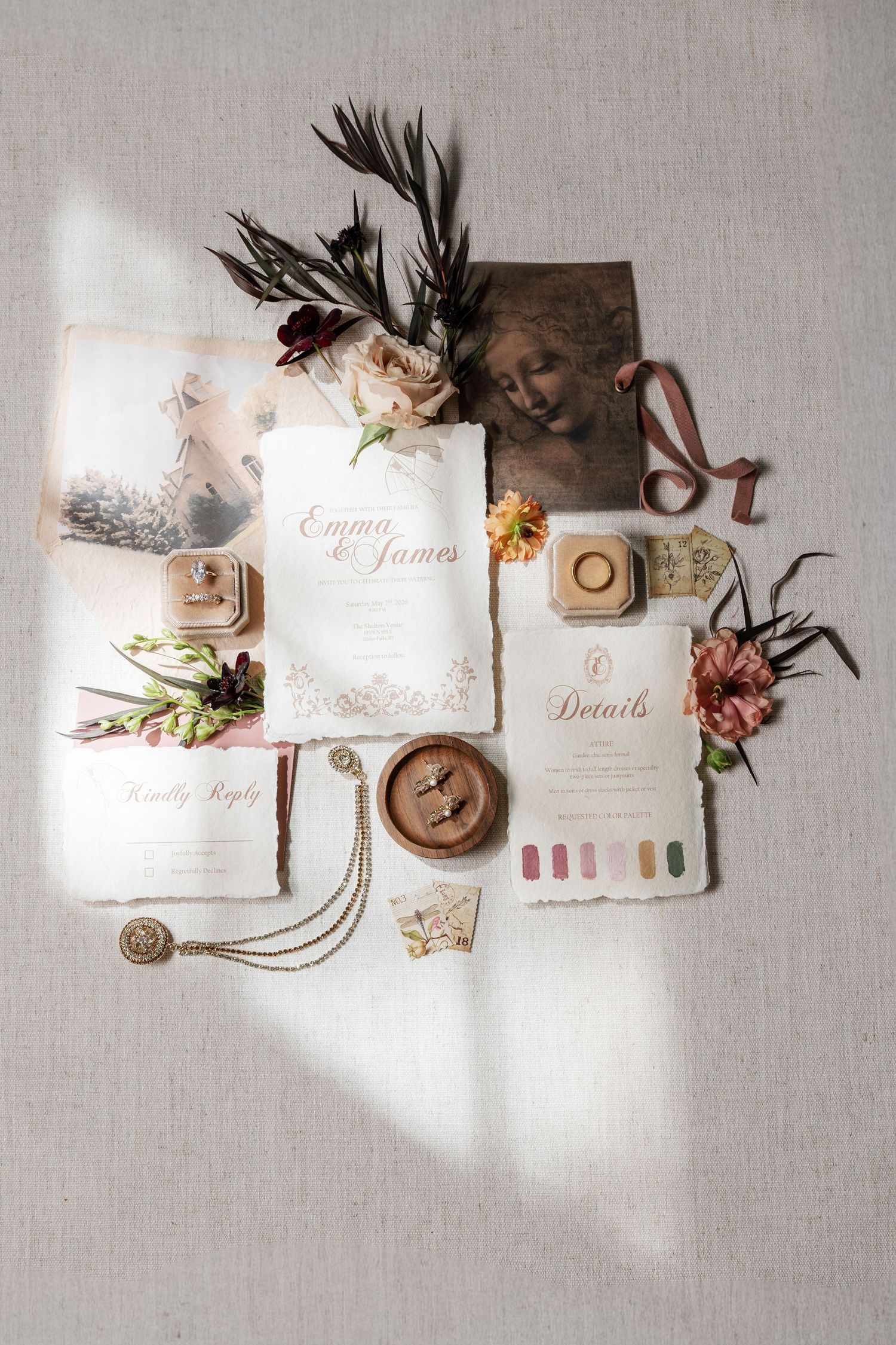 Elegant wedding stationery flat lay featuring invitations, rings, florals, and accessories in warm earthy tones.