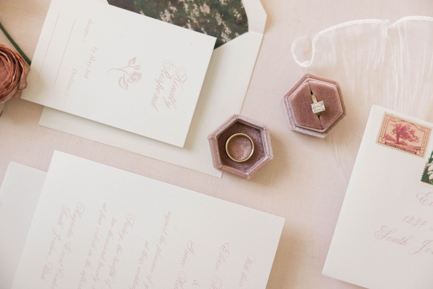 Wedding stationery flatlay featuring pink hexagonal ring dishes and elegant paper details.