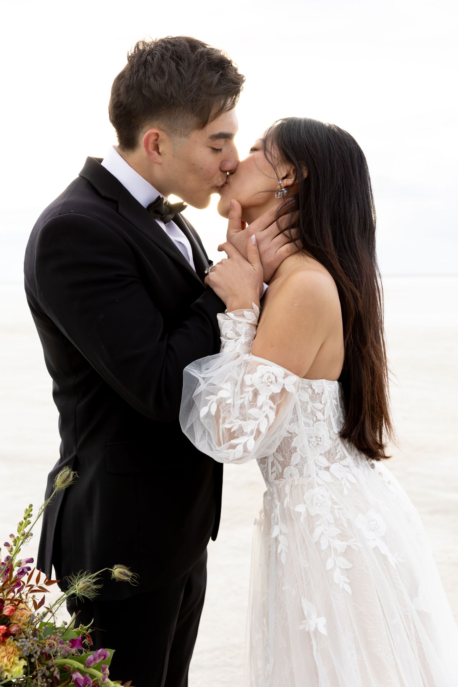Intimate wedding portrait showing a tender moment between newlyweds by the ocean.