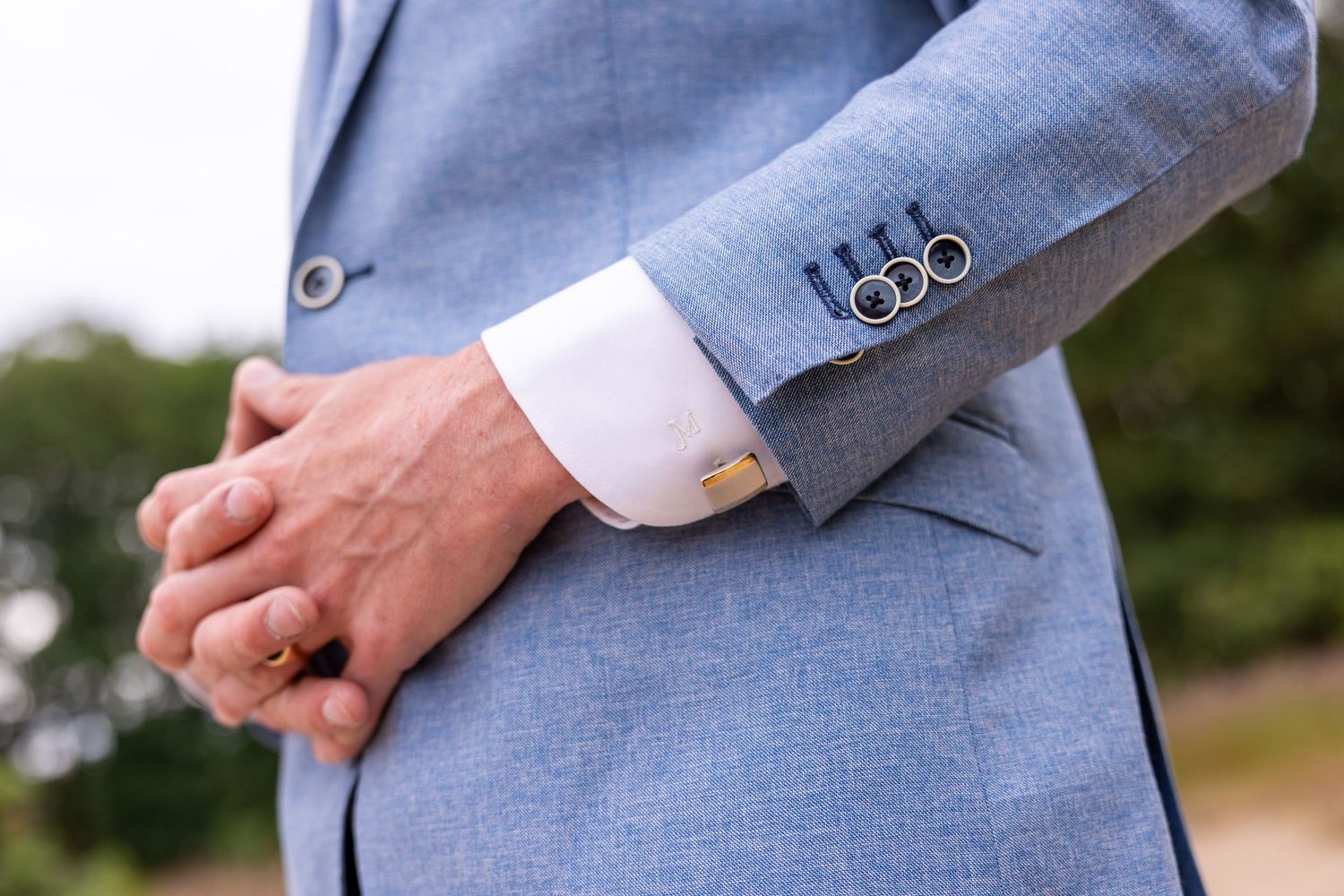 Detail shot of a light blue suit sleeve with decorative buttons.