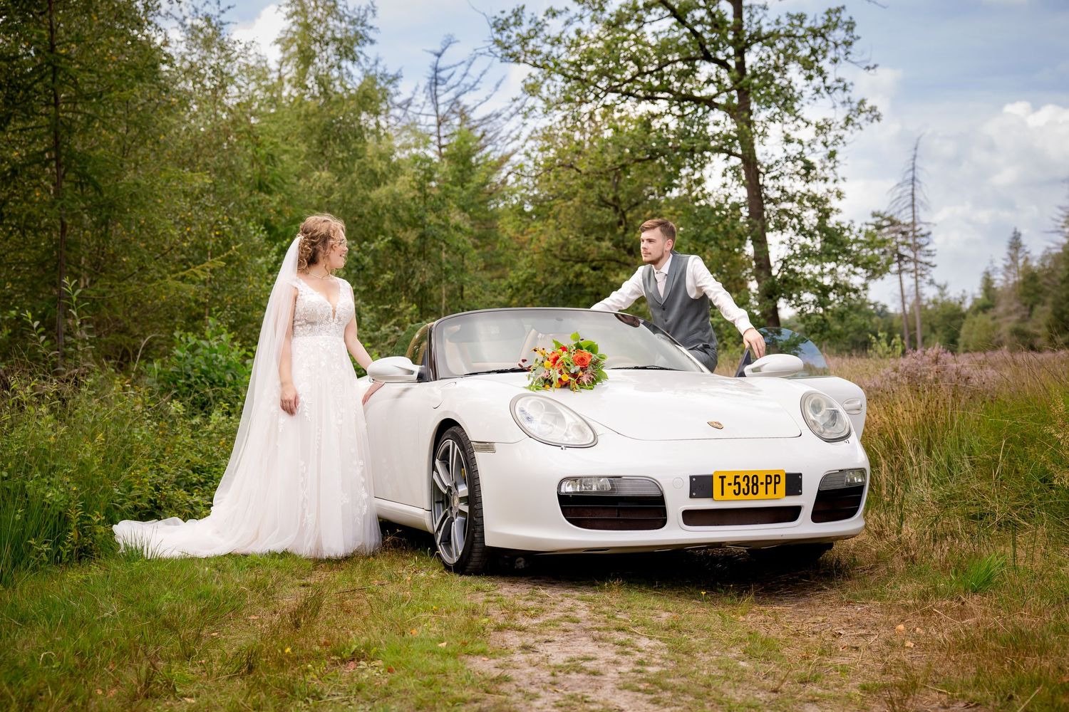 Wedding photography session with classic Porsche car against natural outdoor backdrop.