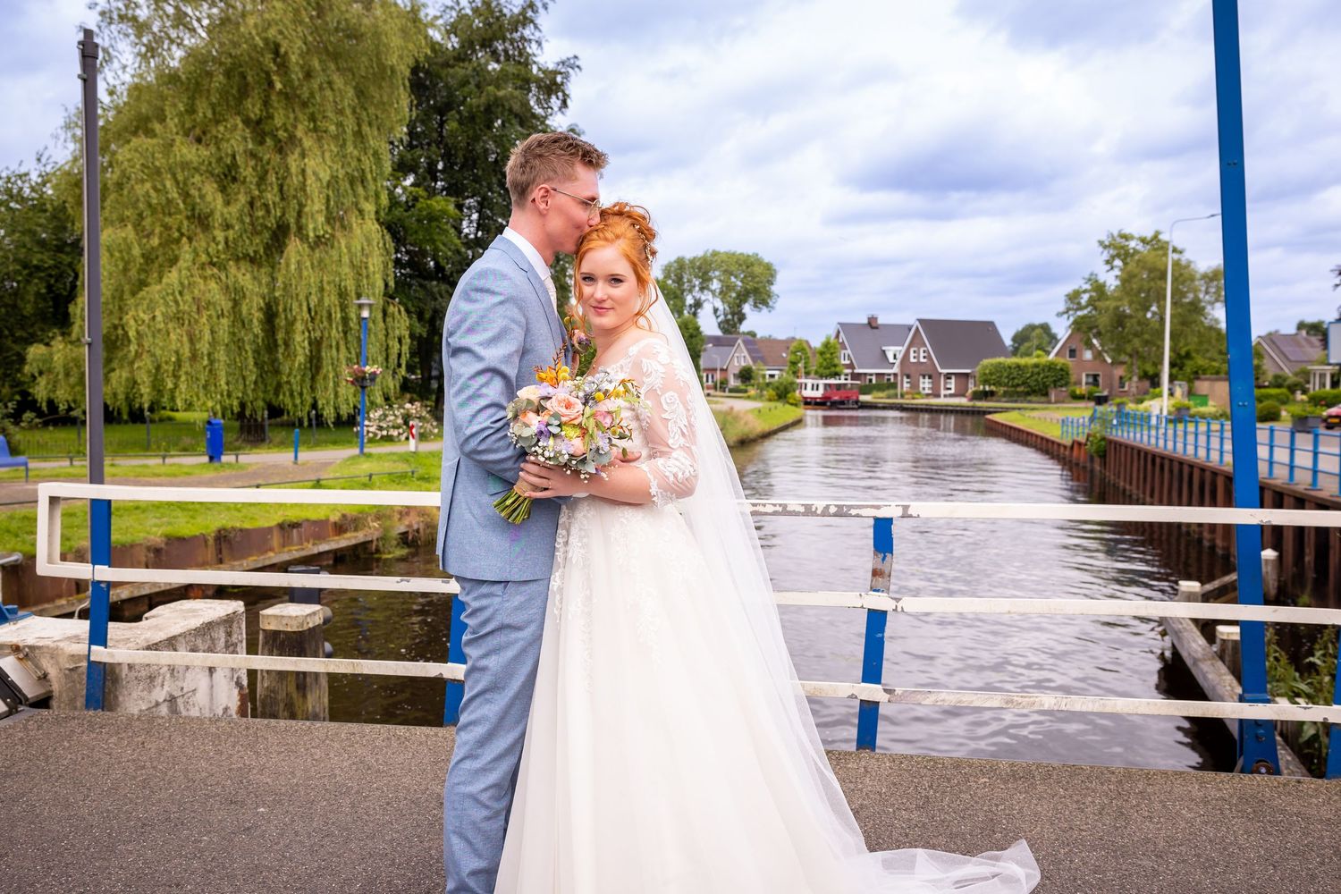 Wedding photography session on a bridge over scenic waterway.