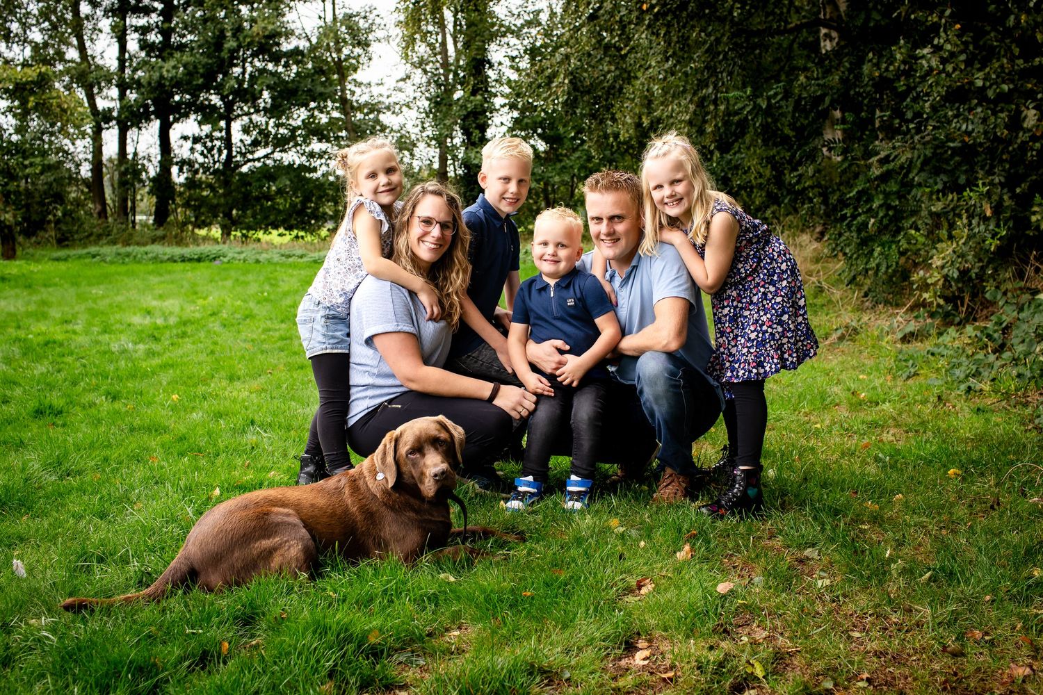 familie poseert in de tuin met vier kinderen en een hond
