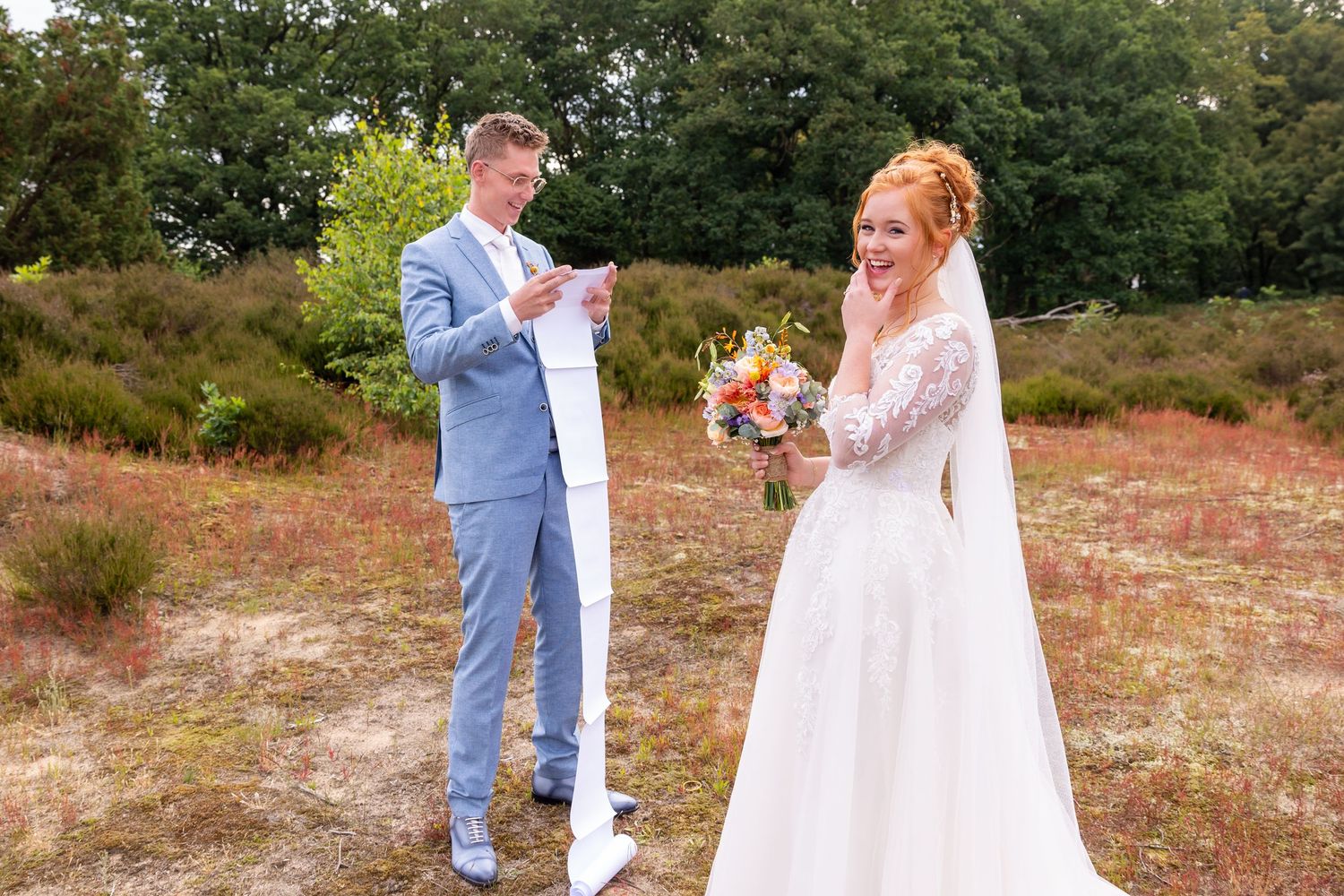 A couple sharing their wedding vows outdoors with a long scroll of paper.