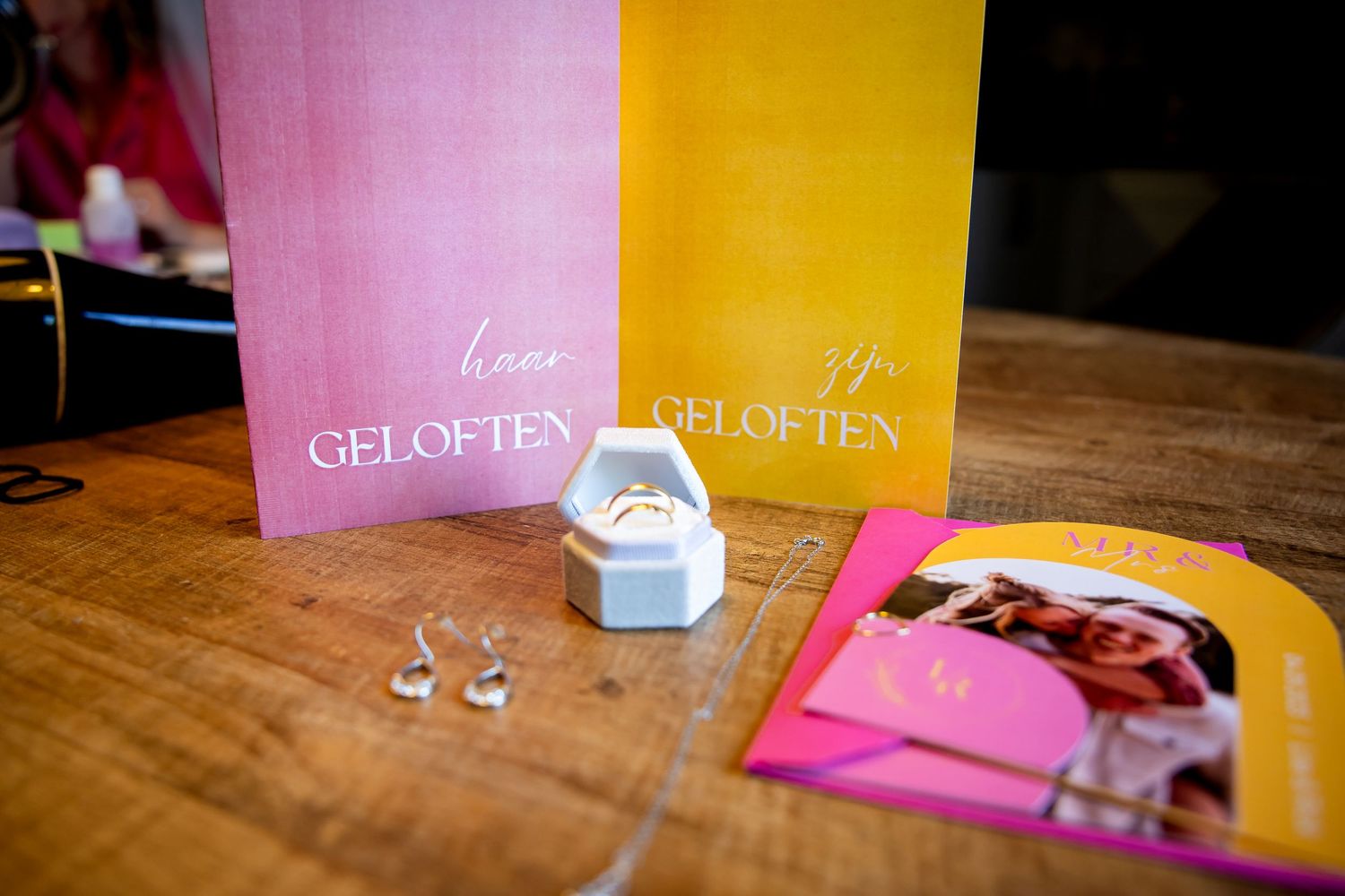 Roze en geel huwelijksuitnodigingen op een houten tafel.