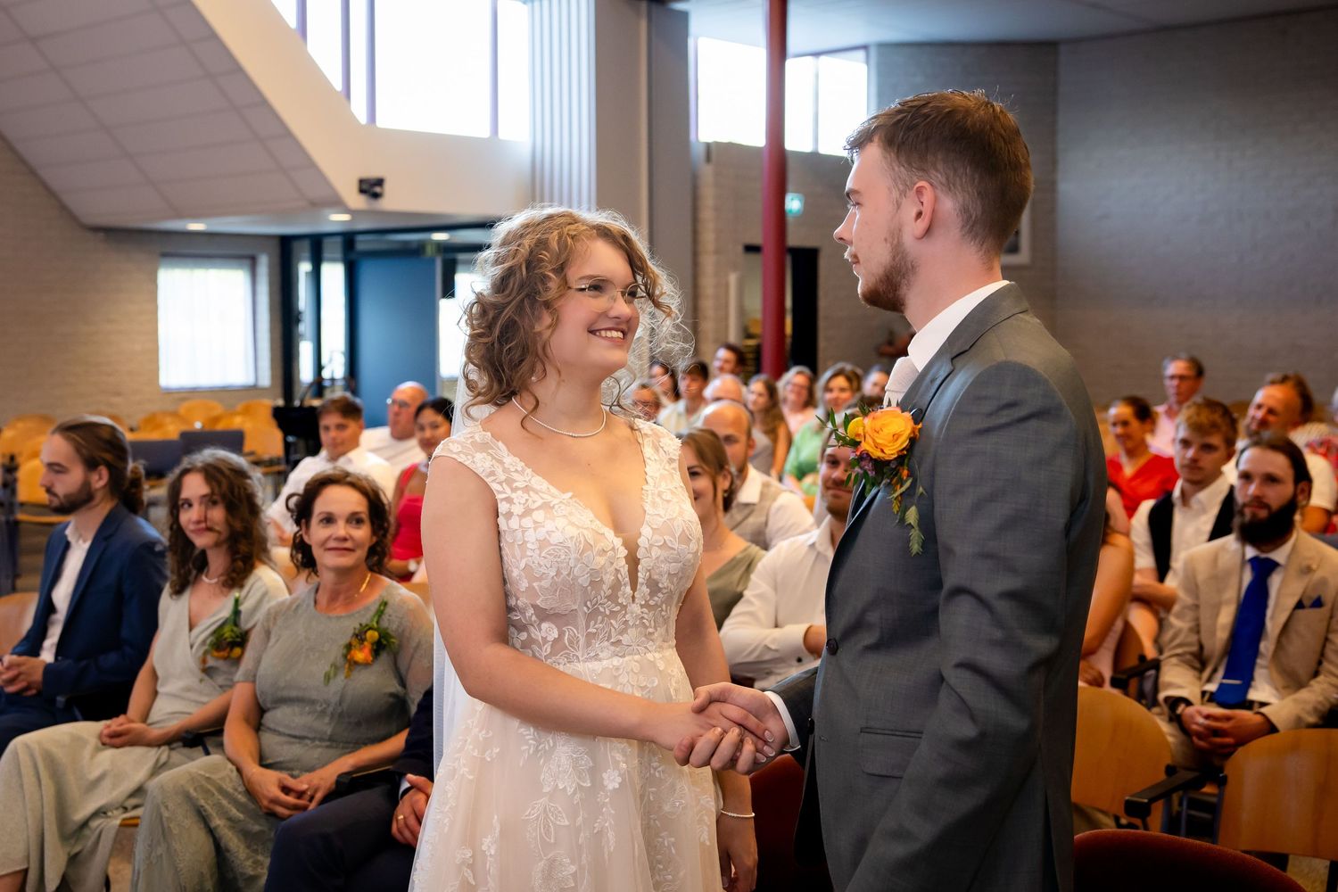 A couple exchanges rings during their wedding ceremony in front of guests.