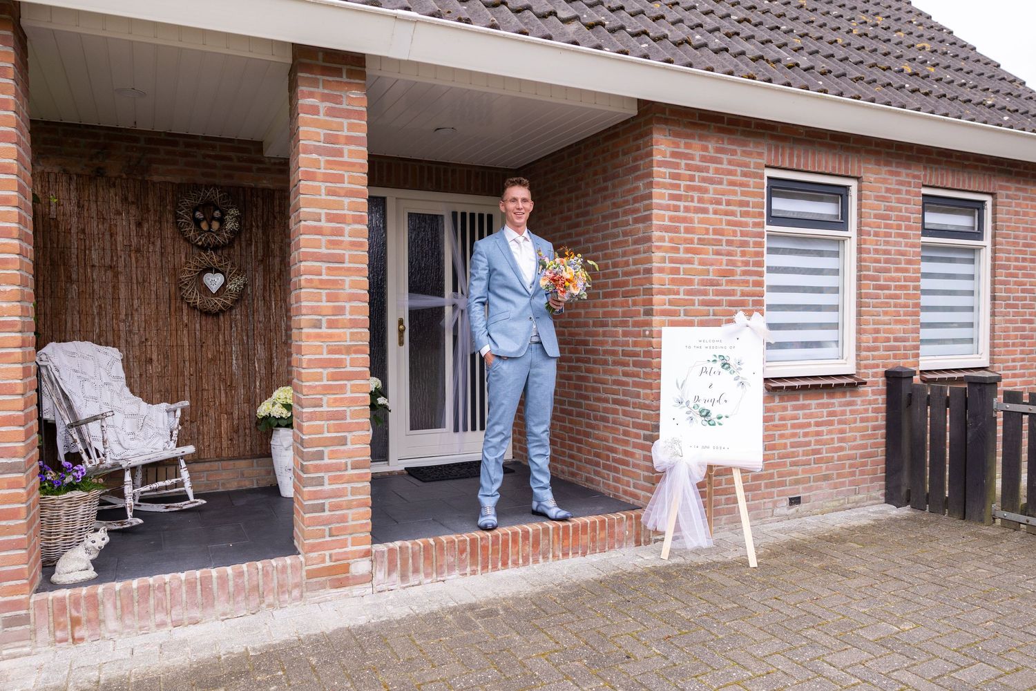 A house entrance with brick porch featuring a welcome sign and rocking chair.