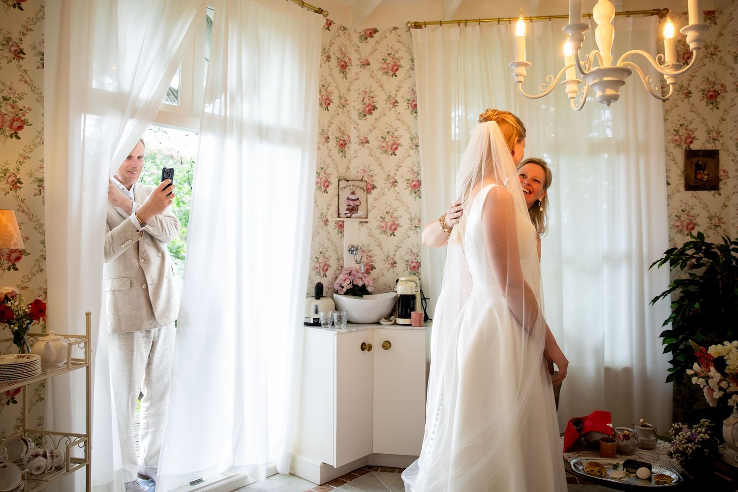 Elegant room with floral wallpaper, sheer white curtains, and warm lighting.