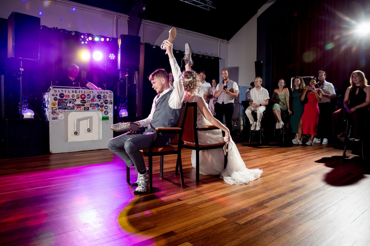Wedding reception venue with colored lighting and wooden dance floor.
