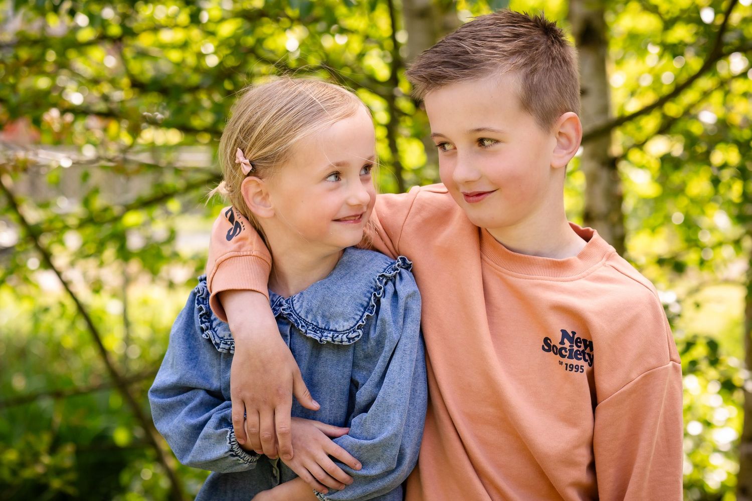 Couple embraces tenderly in a sun-dappled garden setting with golden bokeh lighting in the background.