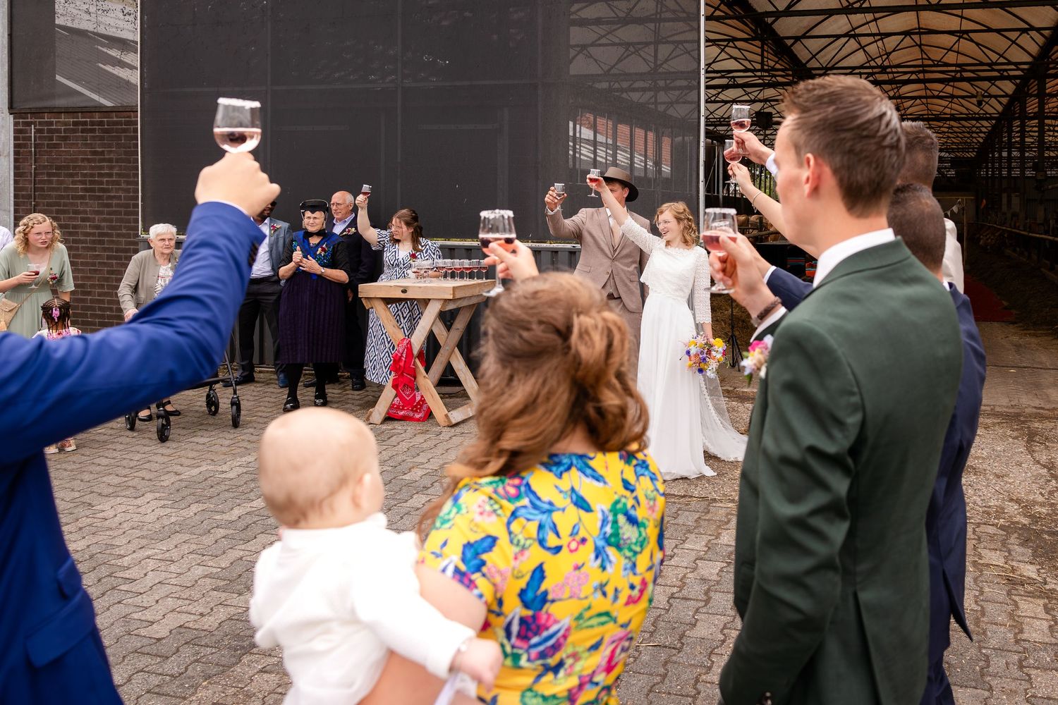 Wedding guests toasting with champagne glasses at an outdoor reception.