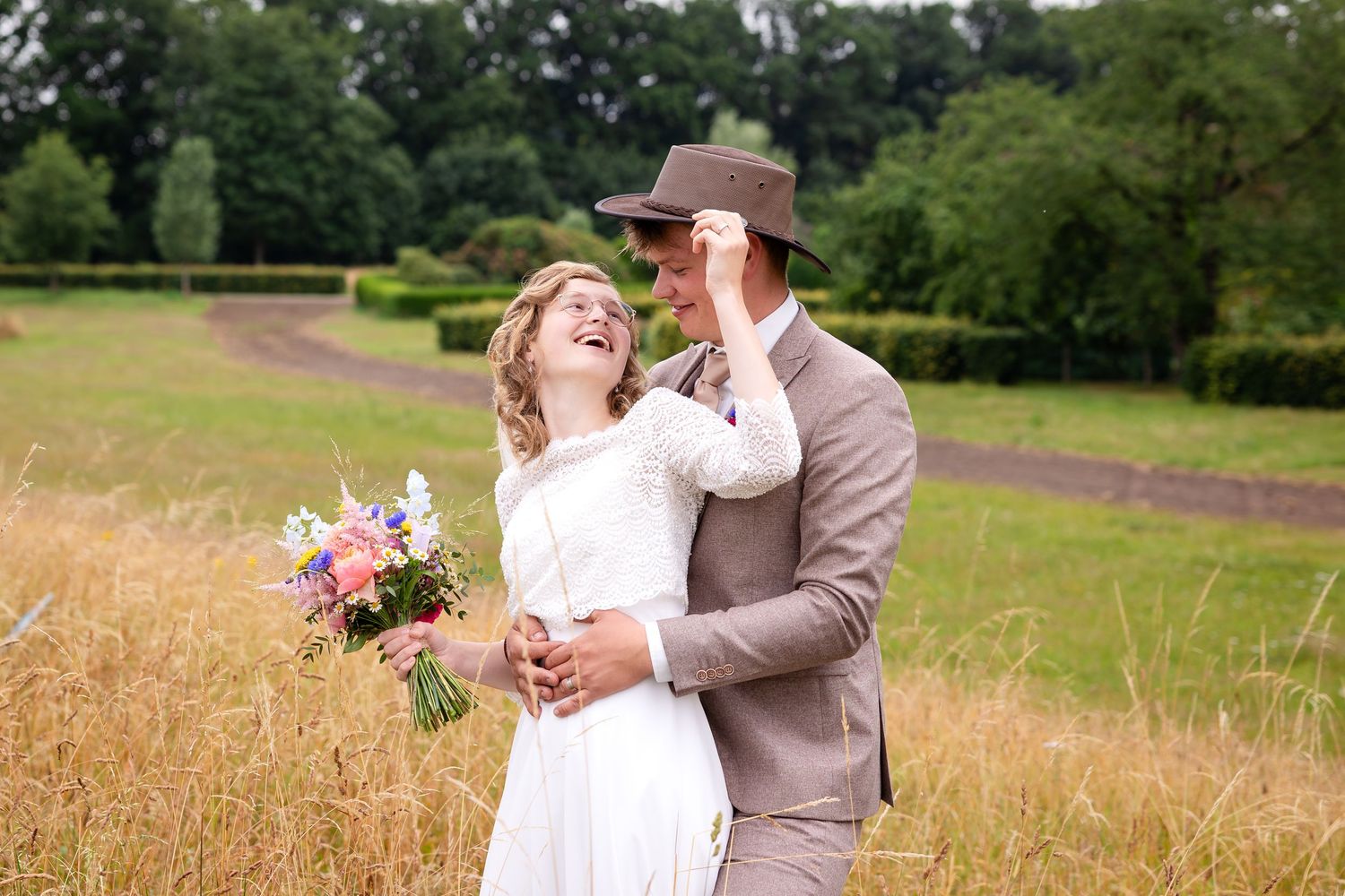 A joyful wedding moment captured in a rustic field with vibrant floral bouquet.