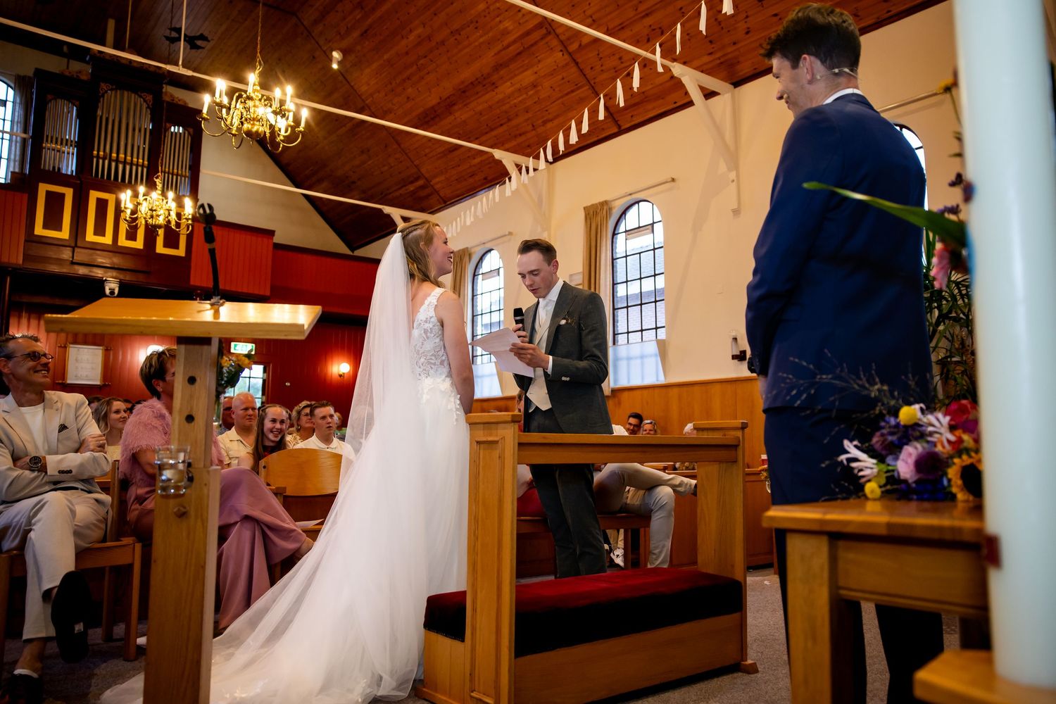 Traditionele kerkelijke huwelijksceremonie met elegante decoratie en warme binnenverlichting.