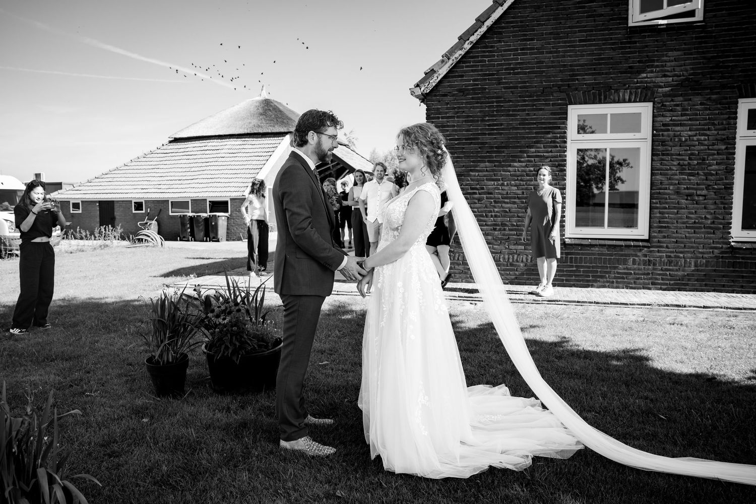 Black and white wedding first look photos in front of rustic farmhouse.