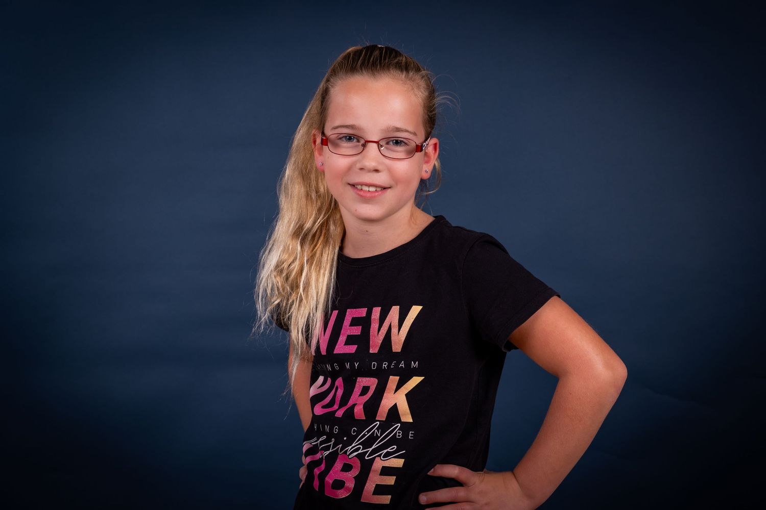Children in casual t-shirts posing together for a family photo against dark background.