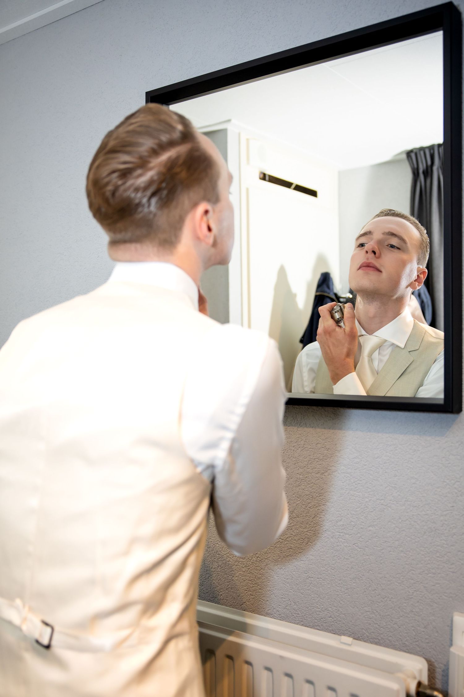 bruidegom doet parfum op ter voorbereiding aan zijn trouwdag