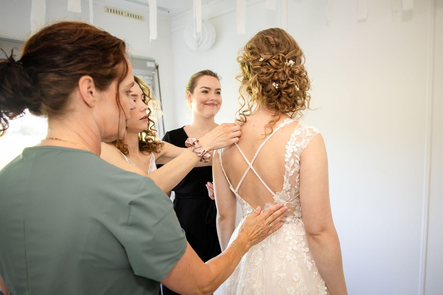 Wedding dress being carefully adjusted and fitted in a bright room.