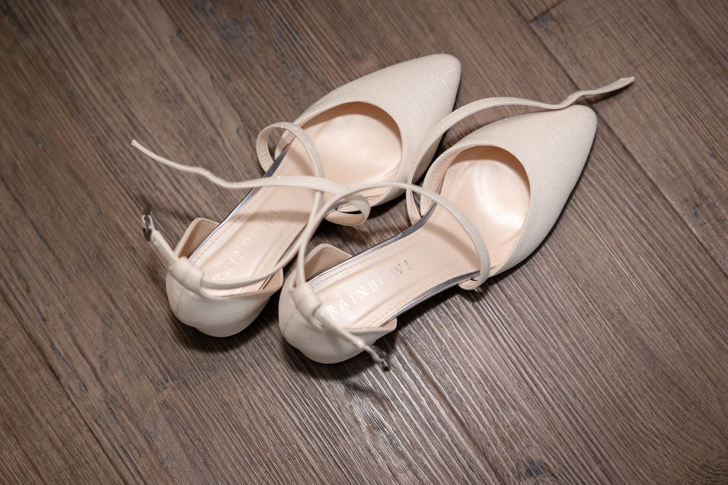 White formal shoes displayed on dark wooden flooring.