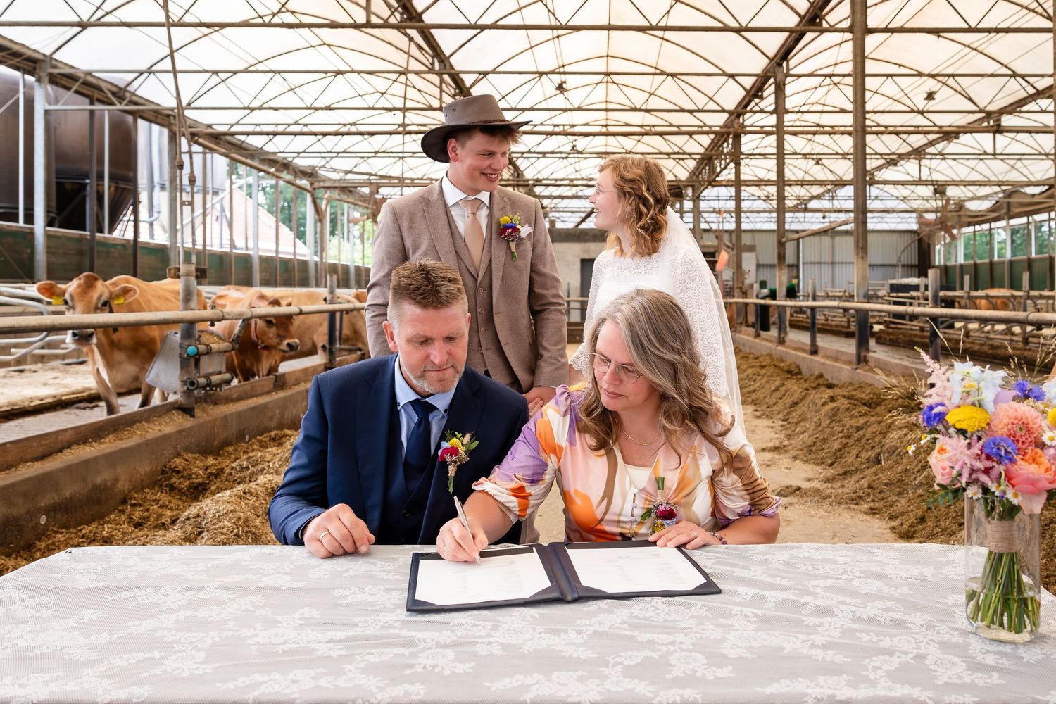 Couple signing marriage documents in a rustic barn venue.