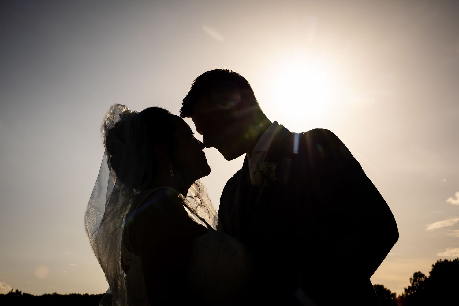 Silhouetted couple embraces during sunset creating a romantic wedding portrait.