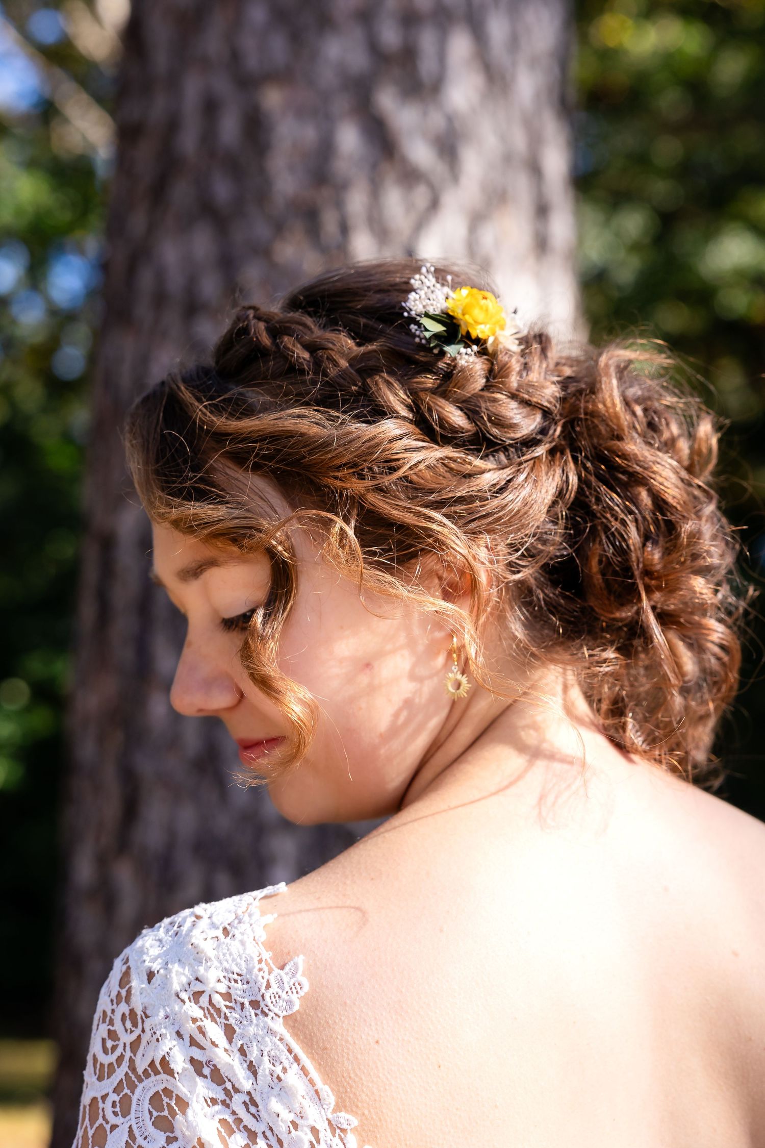 Close-up details of bridal hairstyle with delicate yellow flower accent.