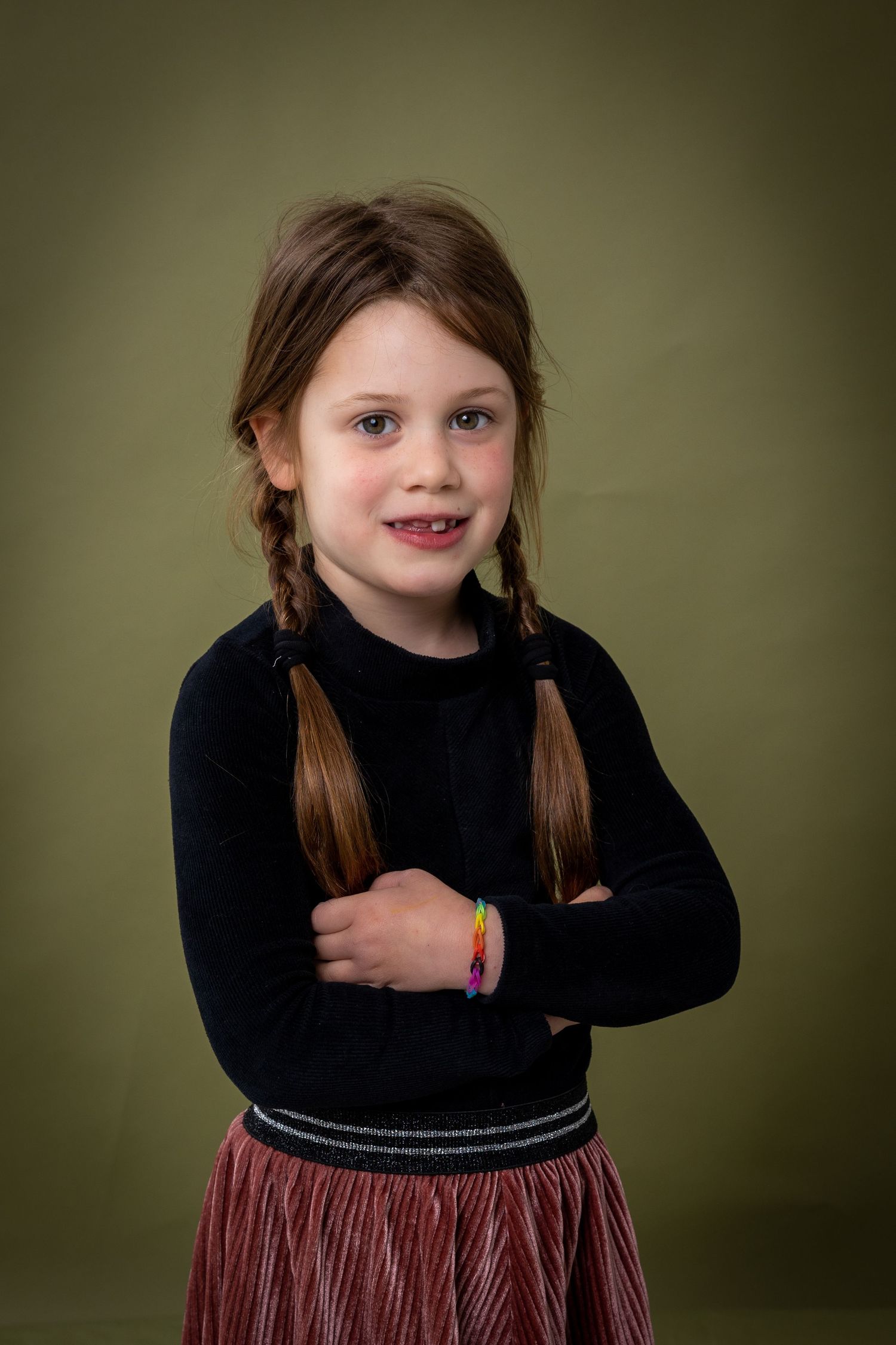 A series of five photos showing a child in a black top and burgundy skirt against an olive green background.