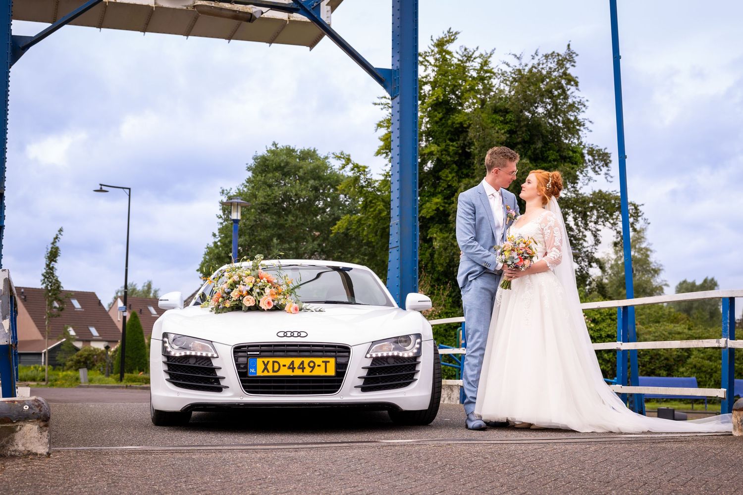 Luxury white sports car displayed under blue metal structure outdoors.