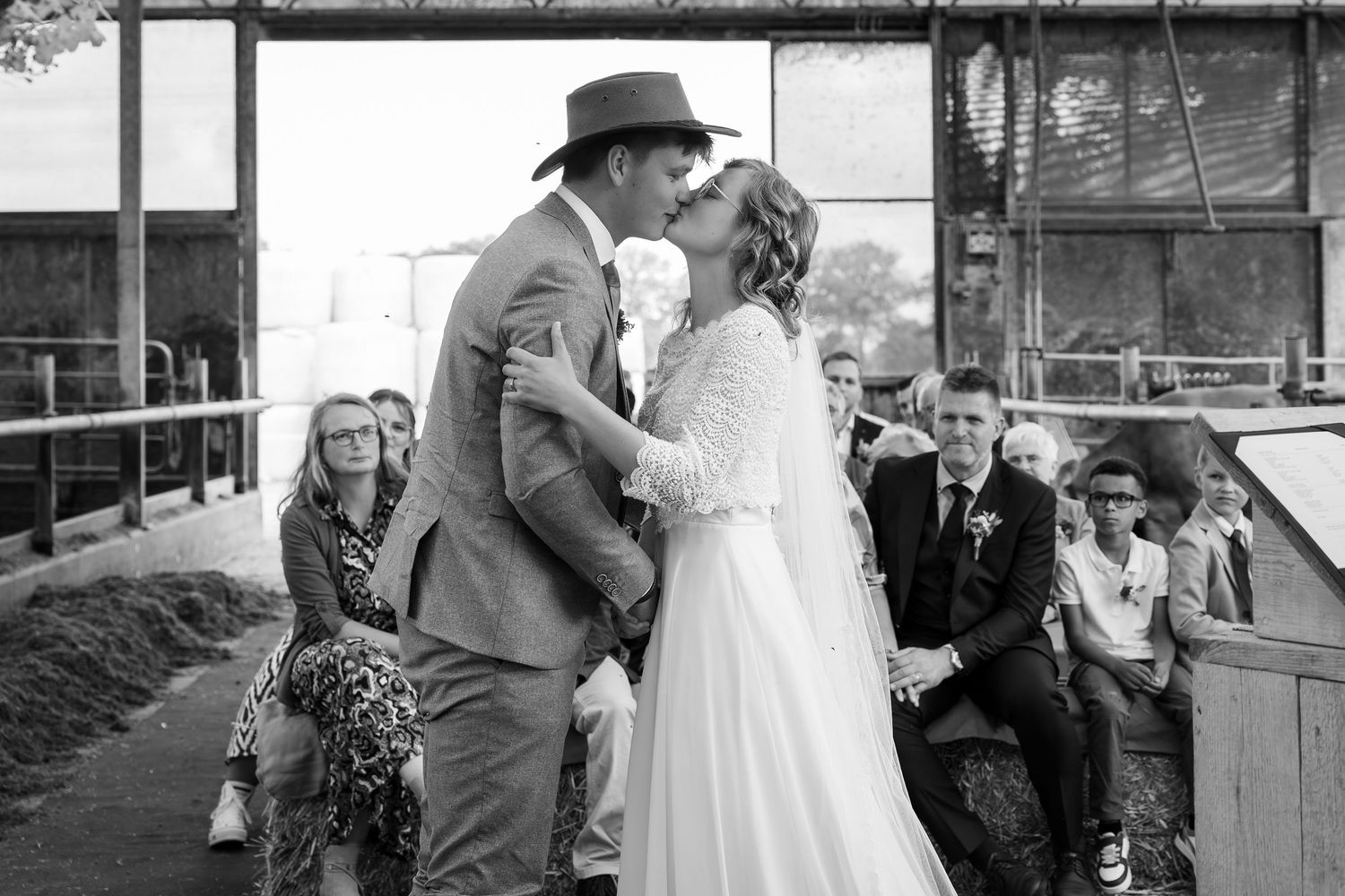 Black and white capture of an intimate wedding moment in a rustic barn setting.