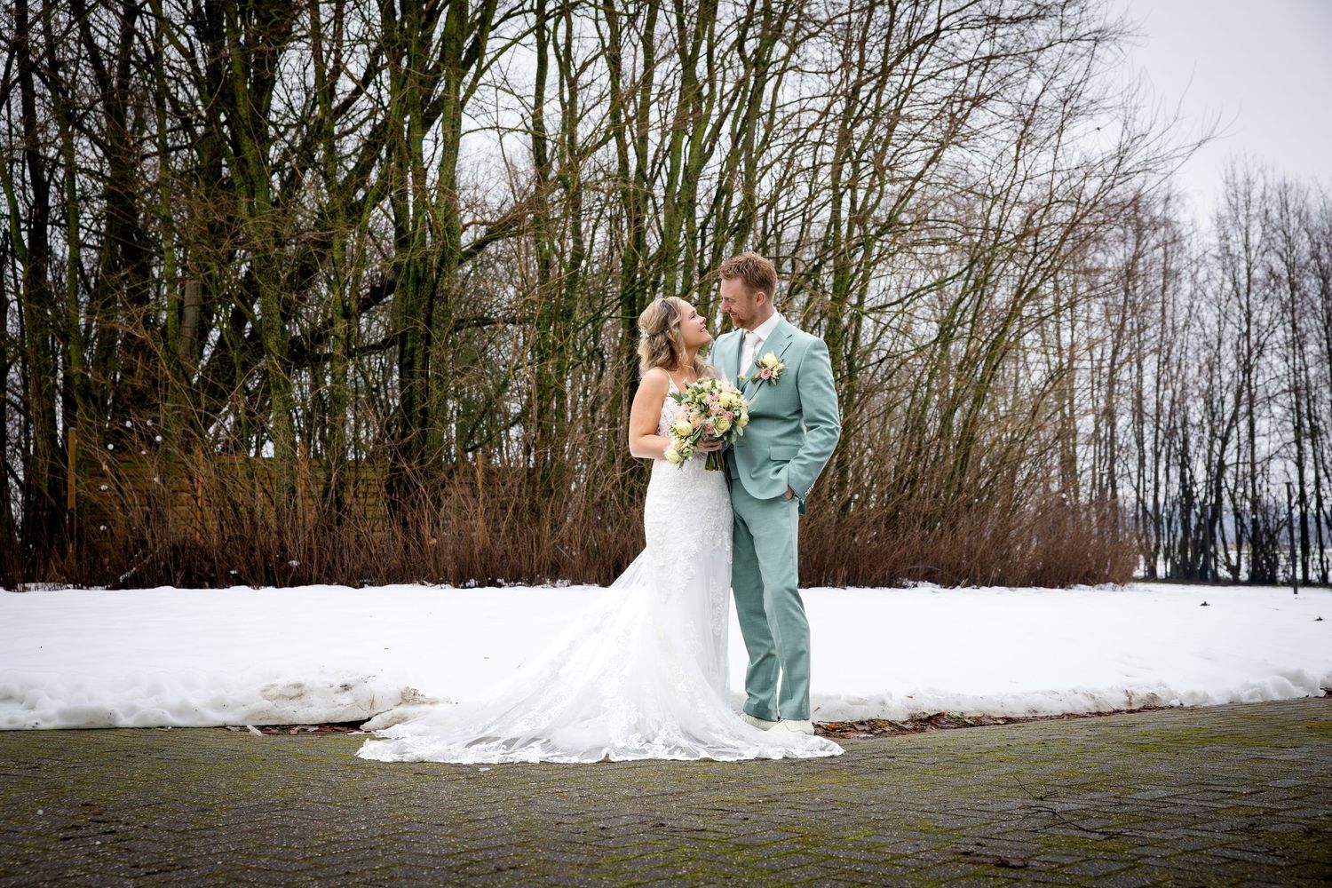 A romantic winter wedding photo shoot featuring couples in formal attire walking through a snowy landscape.