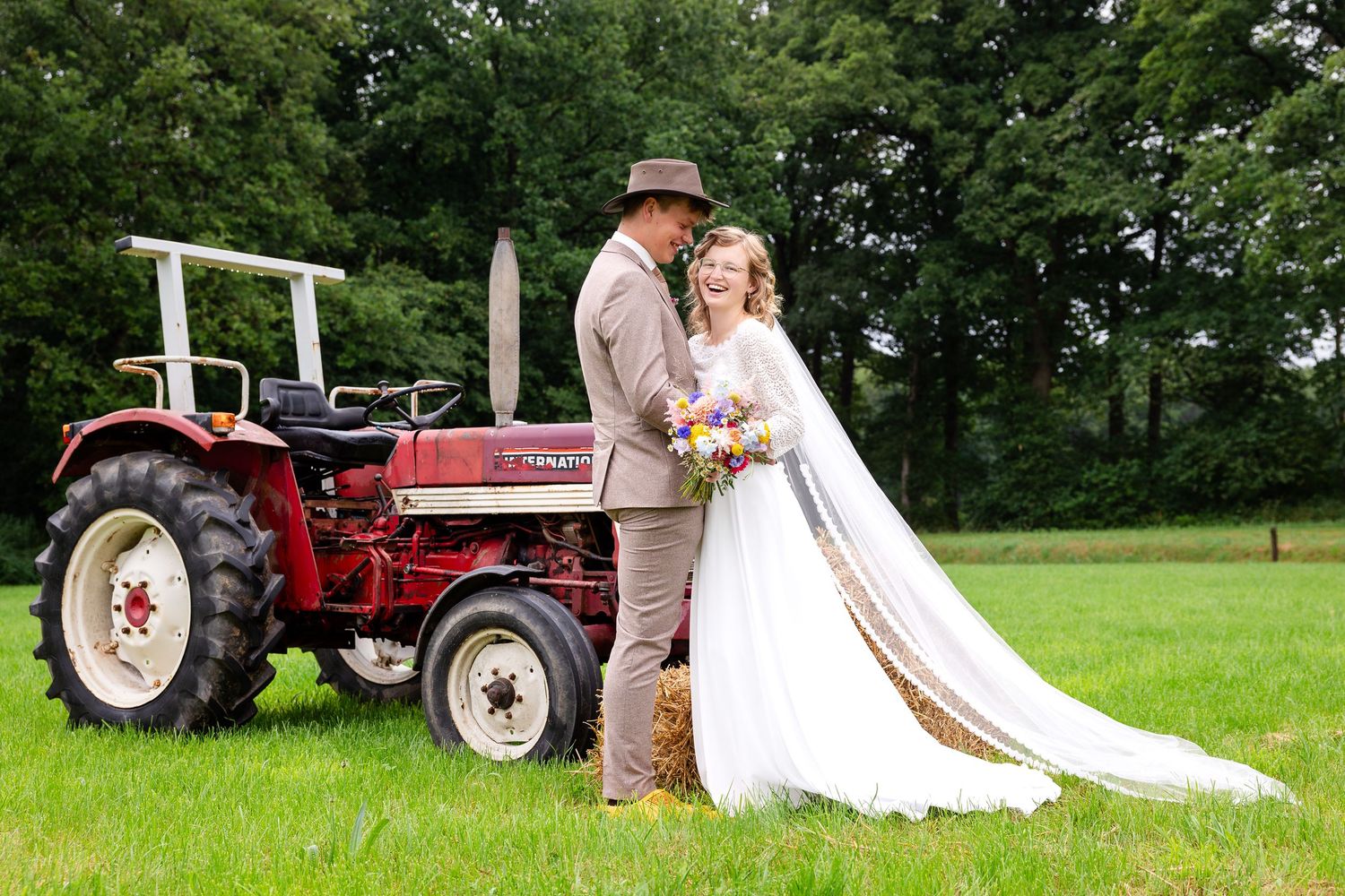 Red tractors and farm equipment arranged for rustic wedding photos in a green field.