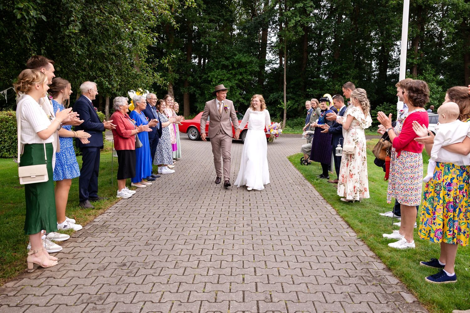 Wedding guests gather along a stone pathway during an outdoor celebration.