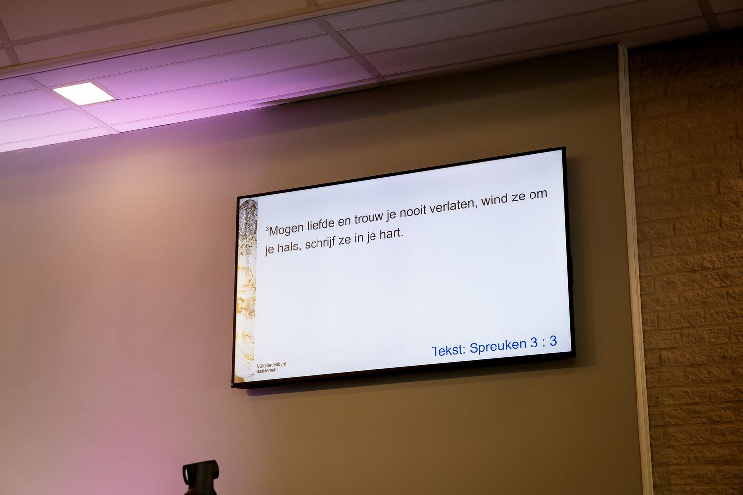 Purple-lit reception venue with digital display screens mounted on brown walls.