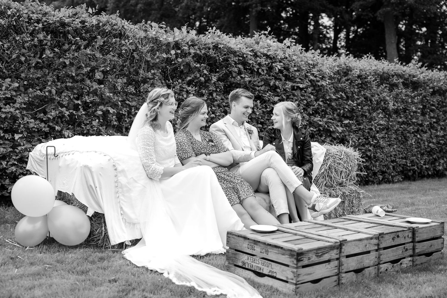 Wedding couple relaxing on wooden pallets in a garden setting.
