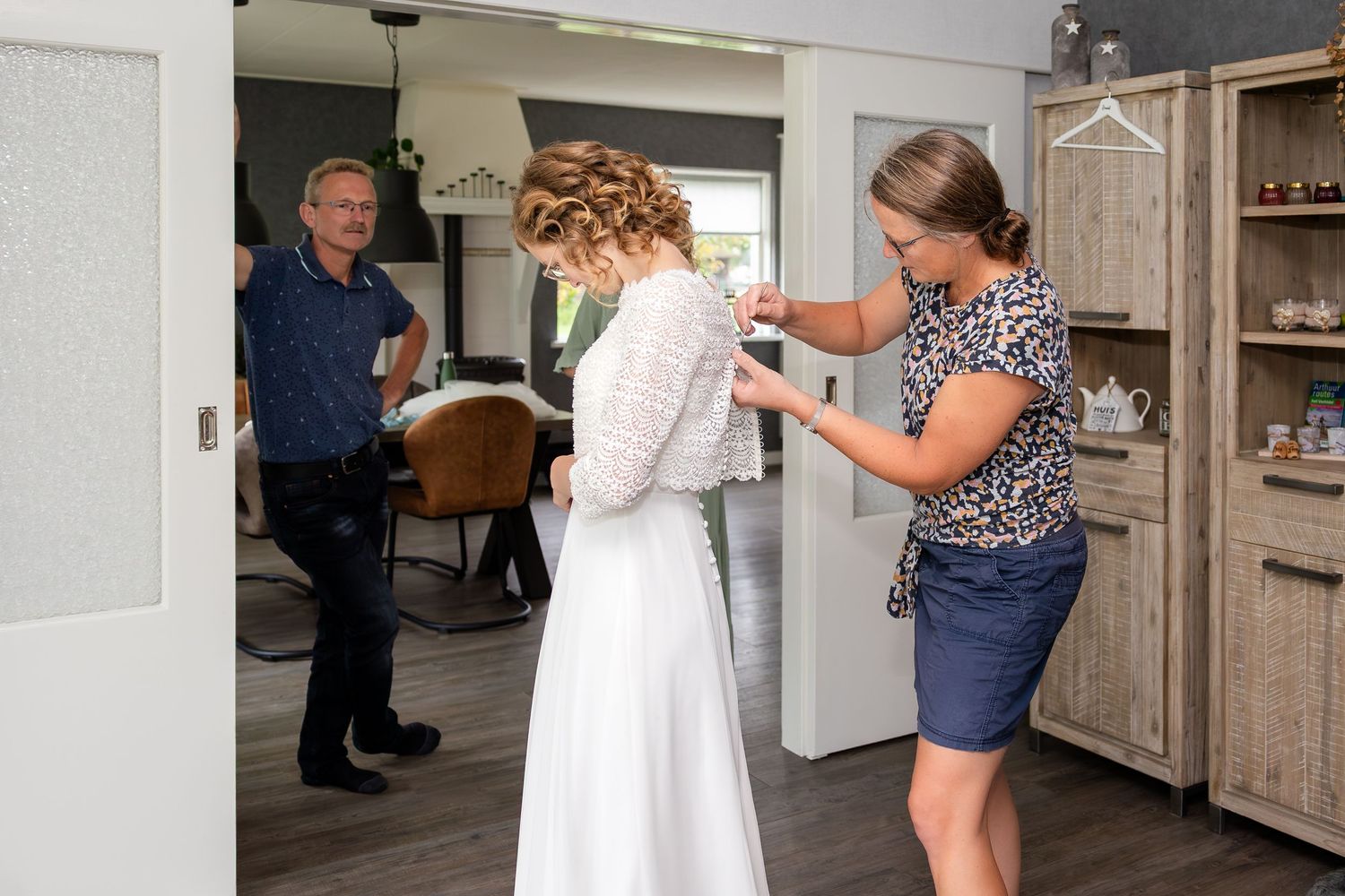 People helping with formal dress preparations in a kitchen setting.