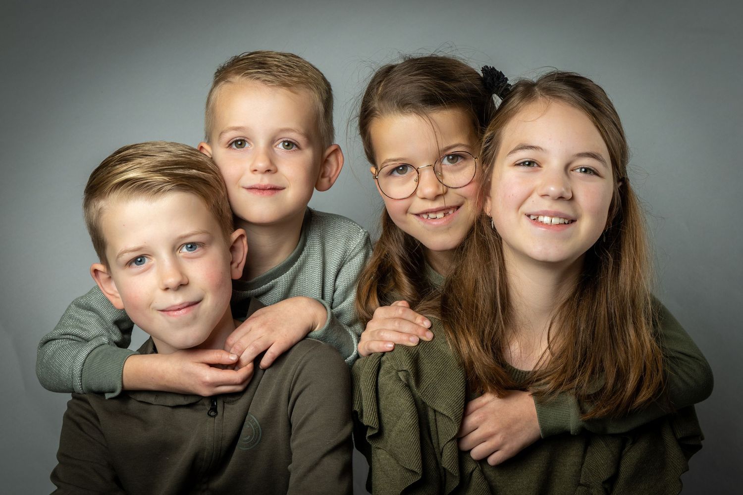 A series of five connected black and white portrait photographs showing siblings in matching olive colored clothing.
