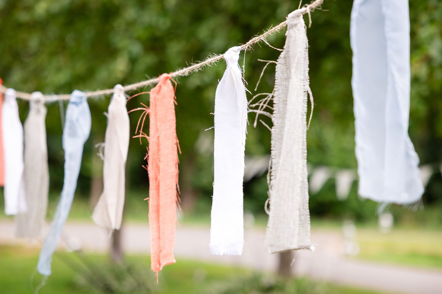 White and pink fabric bunting decorations hanging outdoors for a wedding.
