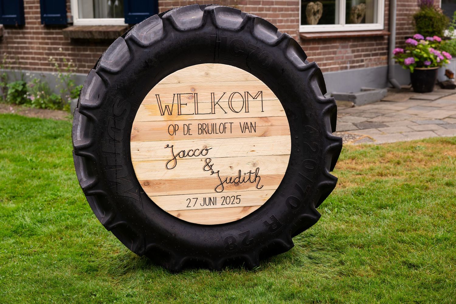 Large tractor tires with wooden welcome signs for a farm wedding celebration.