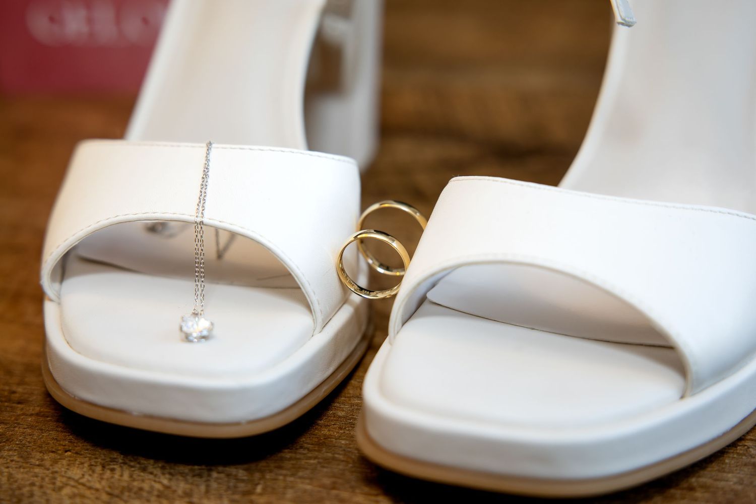 Close-up van elegante witte bruidsschoenen met delicate bandjes , trouwringen en ketting