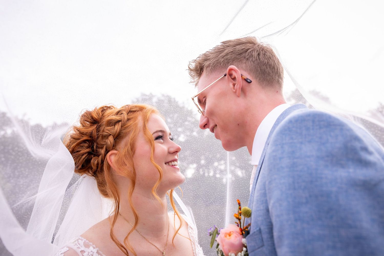 A joyful wedding moment captured under a flowing white veil.