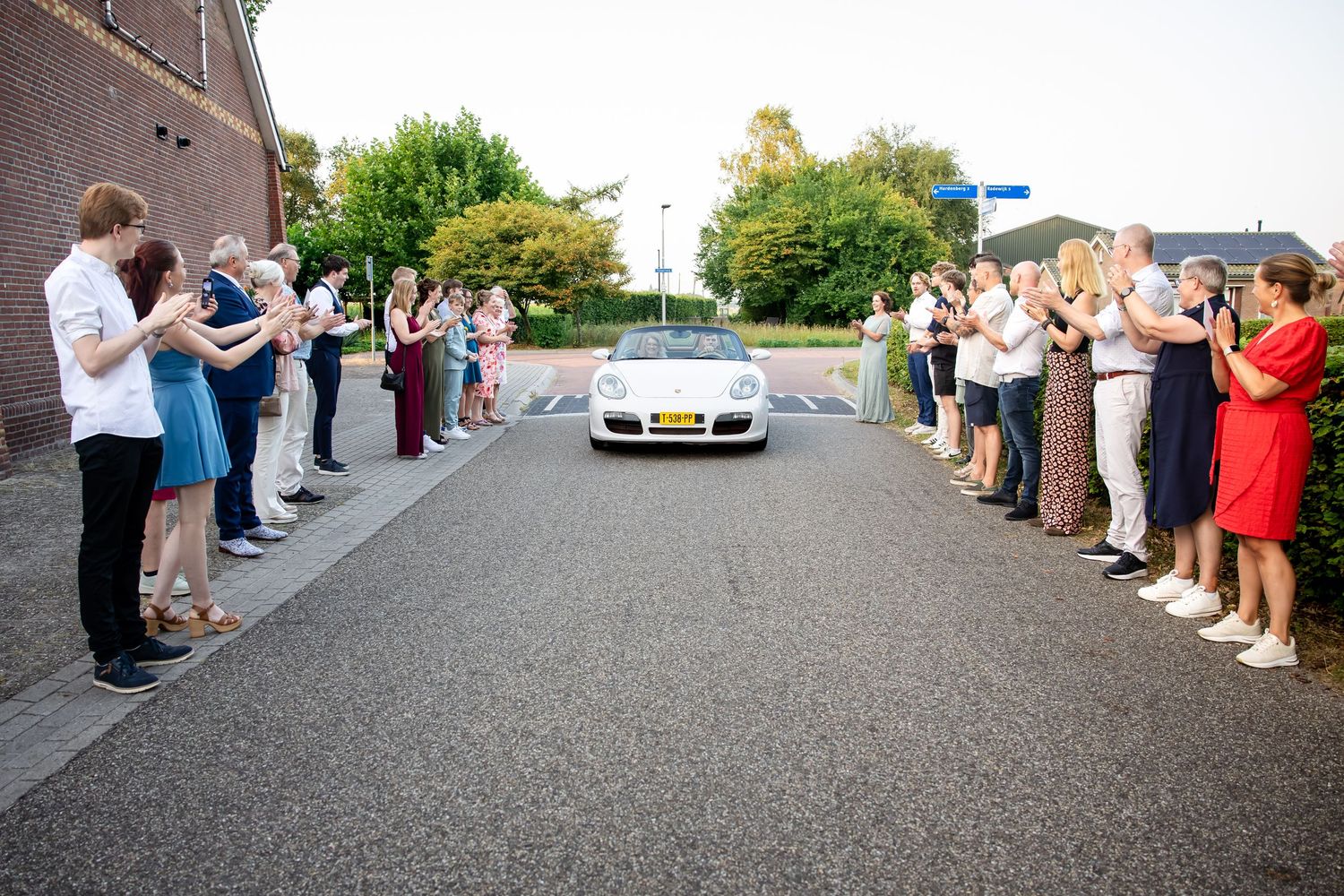 Wedding guests line up outside a brick building to celebrate the newlyweds.