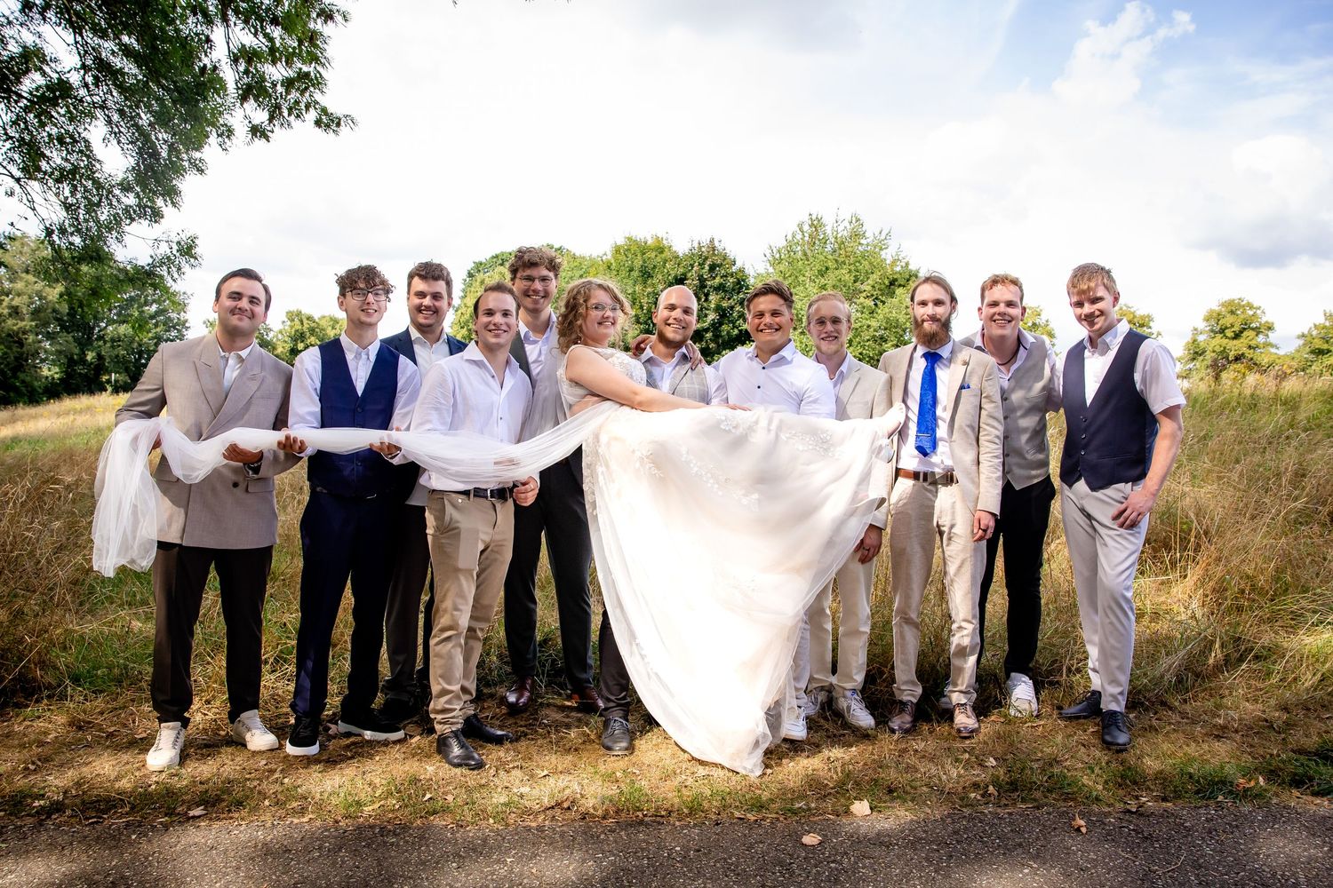 Wedding party poses casually on hillside for group photograph.