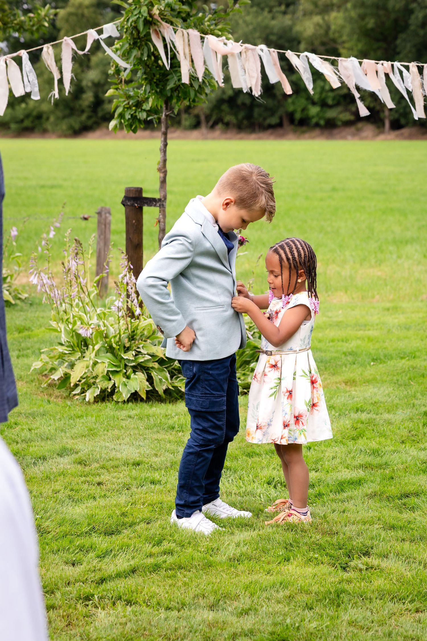 Children playing under white bunting decorations at an outdoor wedding.