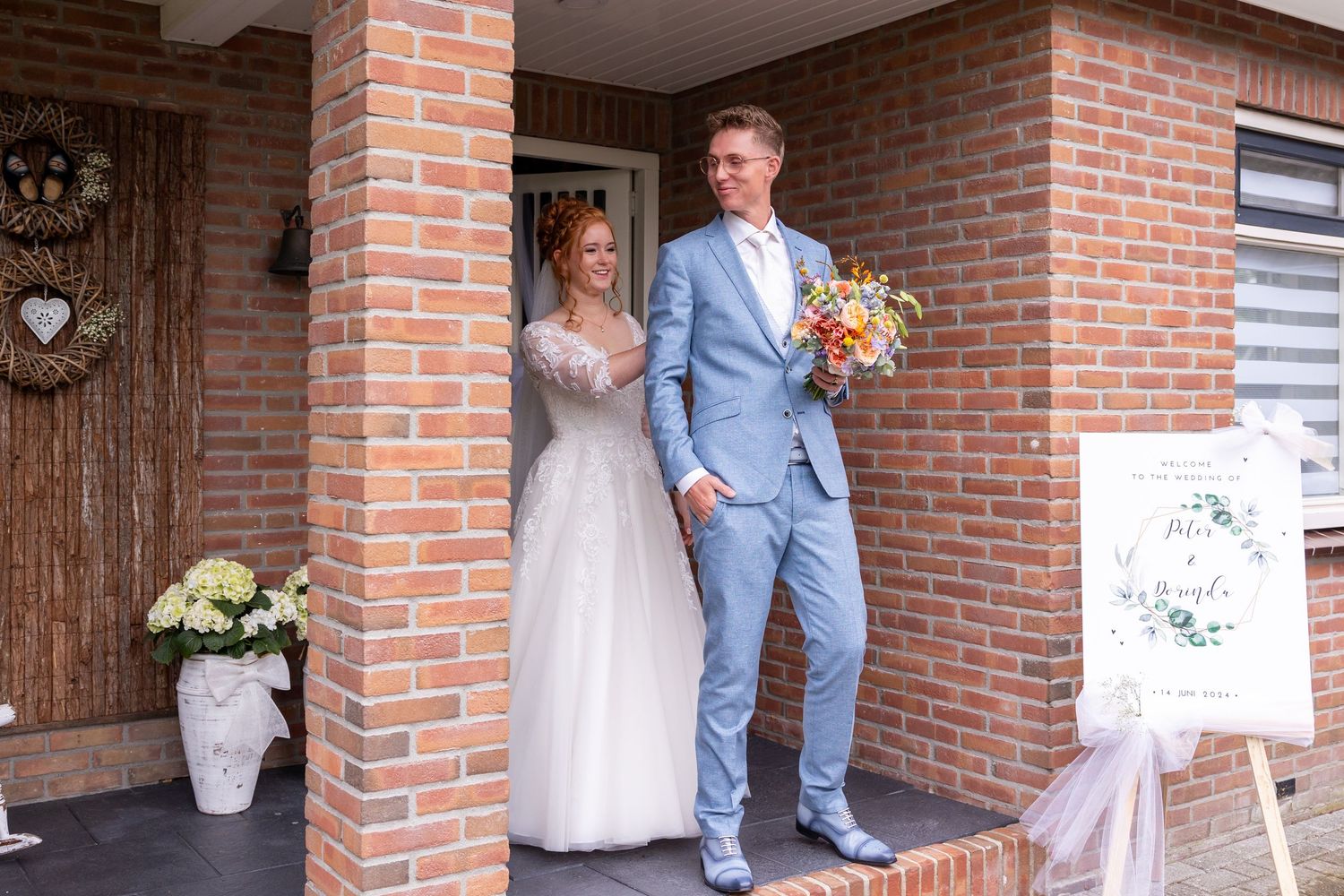 A couple sharing a sweet moment on their wedding day at a brick house entrance.