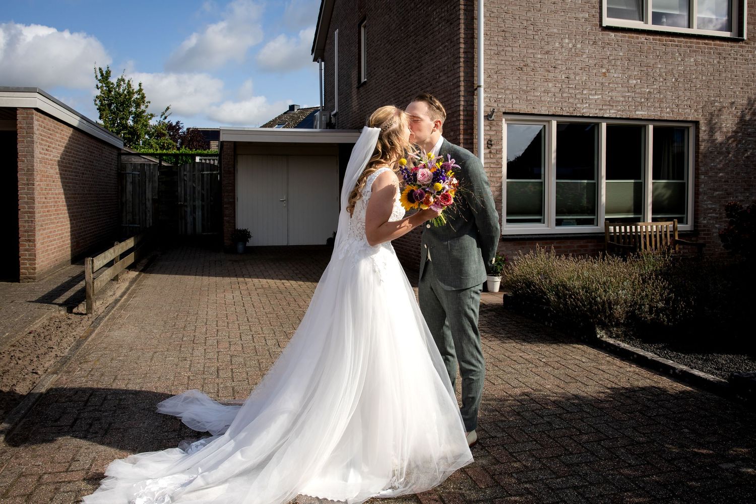 Bruidspaar heeft elkaar zojuist ontmoet en geeft elkaar een zoen in mooi zonnig weer