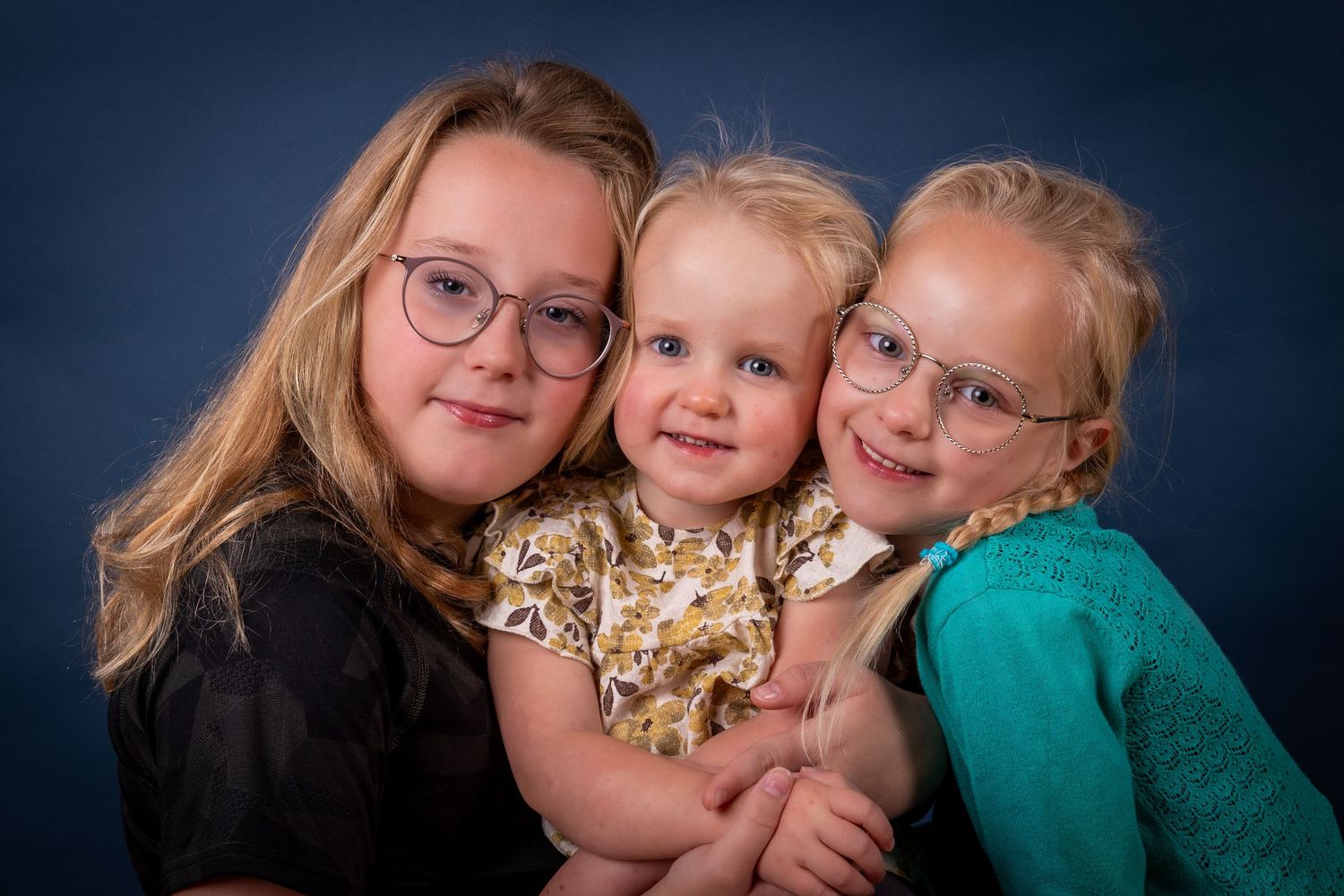 Three people pose together with bright smiles while wearing glasses in a heartwarming family portrait.