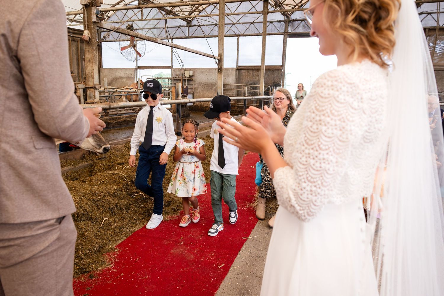 Wedding ceremony taking place in a rustic barn setting with red carpet aisle.
